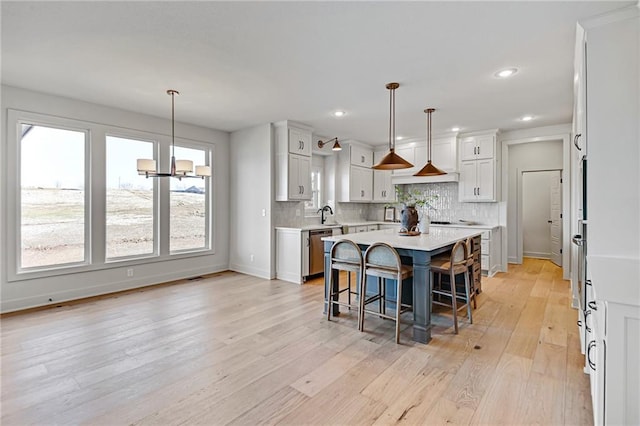 kitchen featuring white cabinetry, decorative light fixtures, a center island, and a kitchen bar