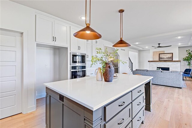 kitchen featuring built in microwave, white cabinetry, gray cabinetry, hanging light fixtures, and stainless steel oven