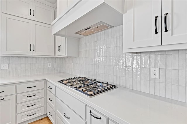 kitchen with white cabinetry, stainless steel gas cooktop, custom exhaust hood, and backsplash