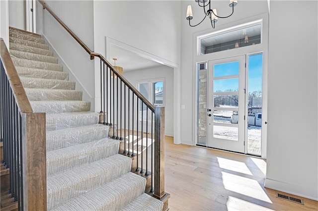 entrance foyer featuring an inviting chandelier, light hardwood / wood-style flooring, and a high ceiling