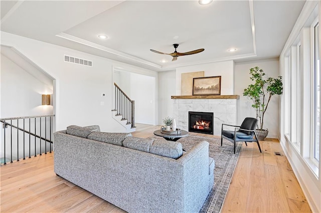 living room with a raised ceiling, ceiling fan, hardwood / wood-style floors, and a fireplace