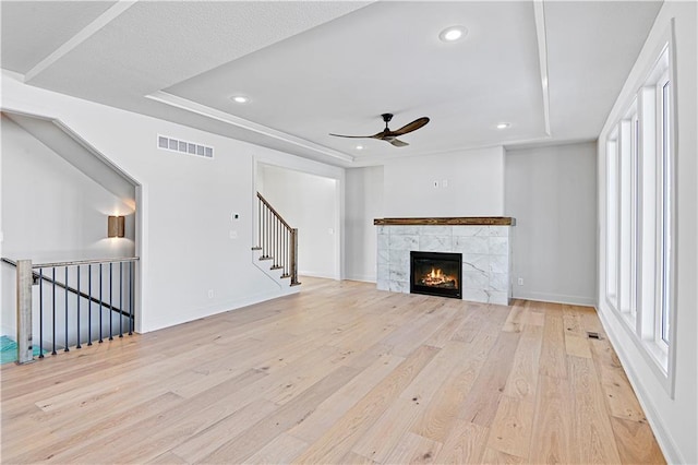 unfurnished living room featuring plenty of natural light, a raised ceiling, and light wood-type flooring