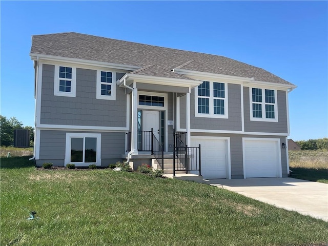 bi-level home featuring a garage, central air condition unit, and a front lawn