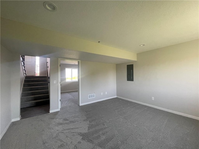 spare room featuring electric panel, dark carpet, and a textured ceiling