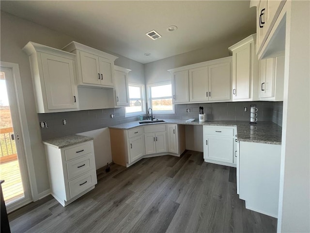 kitchen featuring sink, hardwood / wood-style floors, white cabinets, and decorative backsplash