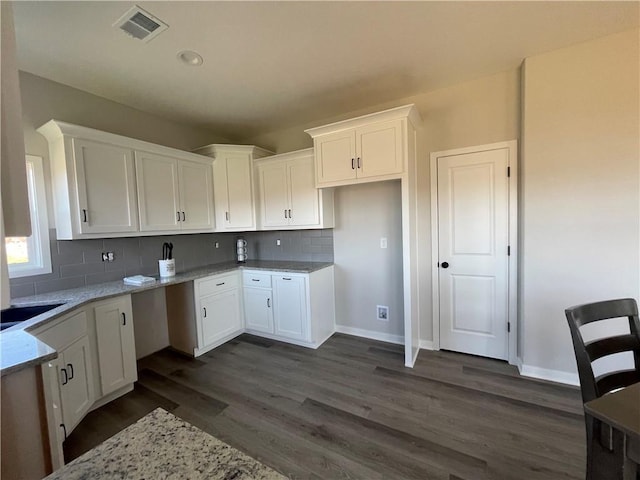 kitchen featuring dark wood-type flooring, white cabinets, light stone counters, and decorative backsplash