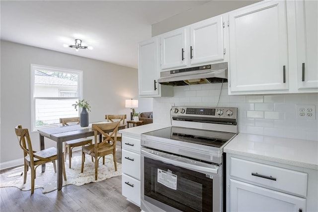 kitchen with light stone counters, stainless steel electric range, white cabinets, light hardwood / wood-style floors, and tasteful backsplash