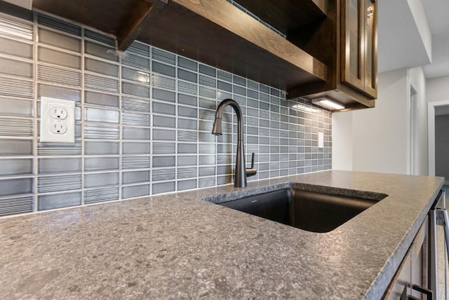 kitchen featuring decorative backsplash, beam ceiling, and sink