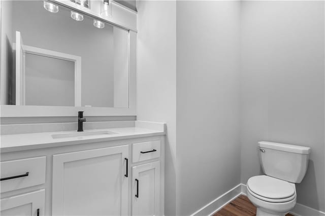 bathroom with hardwood / wood-style floors, vanity, and toilet