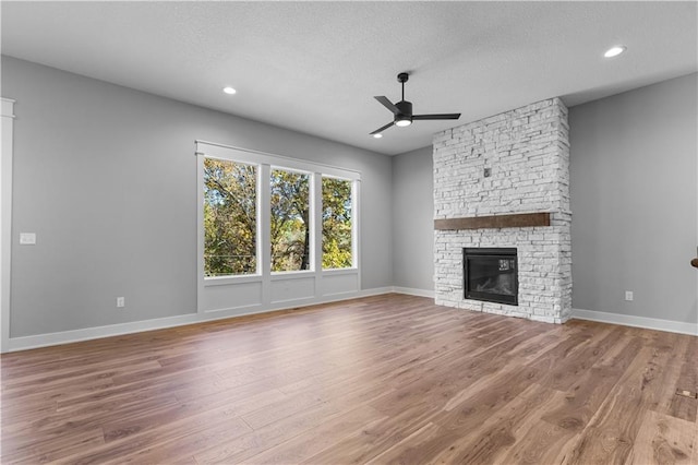 unfurnished living room featuring a fireplace, hardwood / wood-style floors, a textured ceiling, and ceiling fan