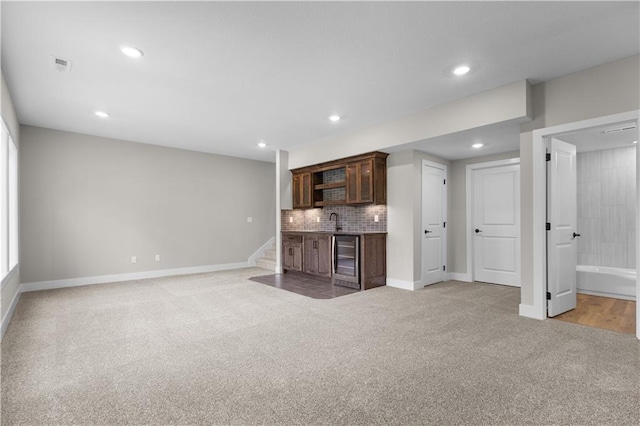 unfurnished living room with light colored carpet, sink, and beverage cooler