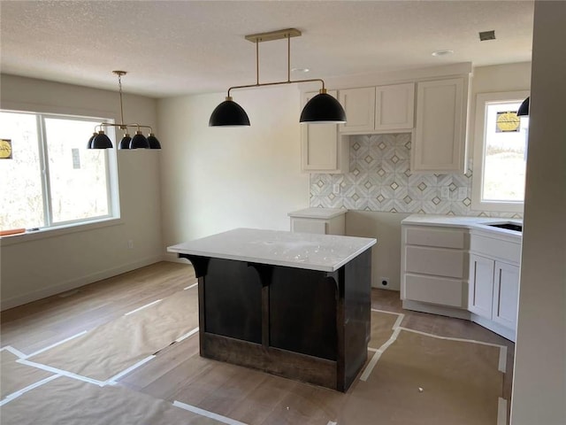 kitchen featuring light wood-type flooring, backsplash, a wealth of natural light, and pendant lighting