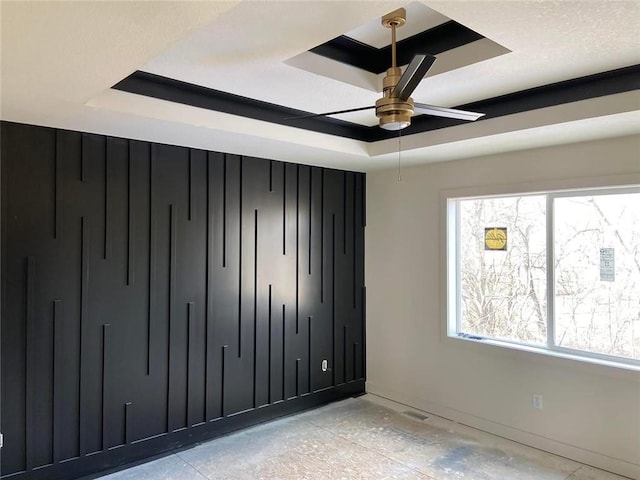 unfurnished bedroom with a tray ceiling and multiple windows