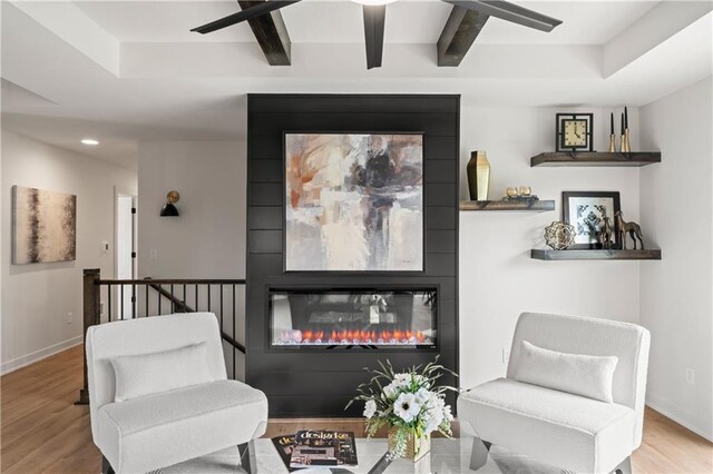 sitting room featuring recessed lighting, beam ceiling, a fireplace, baseboards, and wood finished floors