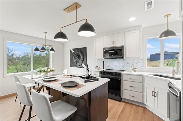 kitchen featuring a sink, appliances with stainless steel finishes, light countertops, a center island, and backsplash