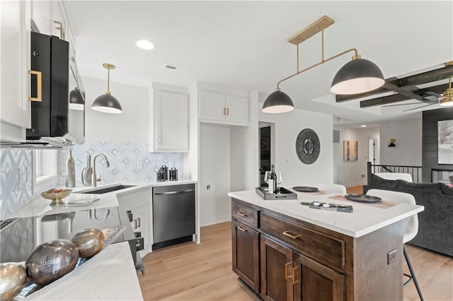 kitchen with a sink, decorative backsplash, visible vents, light countertops, and stainless steel dishwasher
