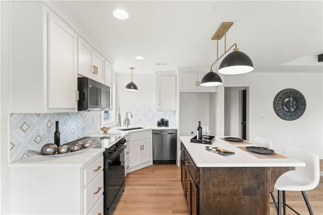 kitchen with a breakfast bar area, black electric range oven, a sink, light wood-type flooring, and dishwasher