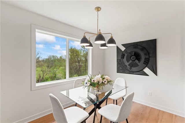 dining area featuring a notable chandelier, light wood-style flooring, and baseboards