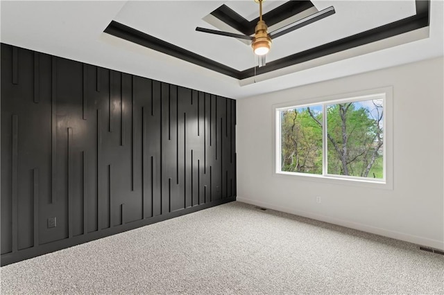 unfurnished bedroom with carpet, visible vents, a tray ceiling, and baseboards