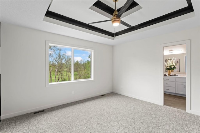 unfurnished bedroom with a raised ceiling, visible vents, baseboards, and light carpet