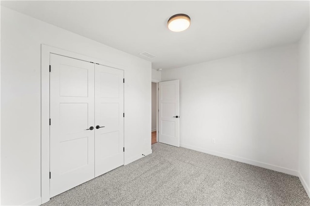unfurnished bedroom with a closet, carpet flooring, visible vents, and baseboards