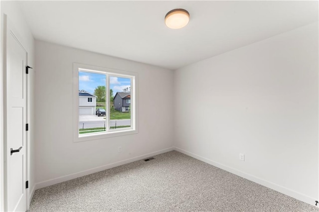 unfurnished room with carpet, visible vents, and baseboards