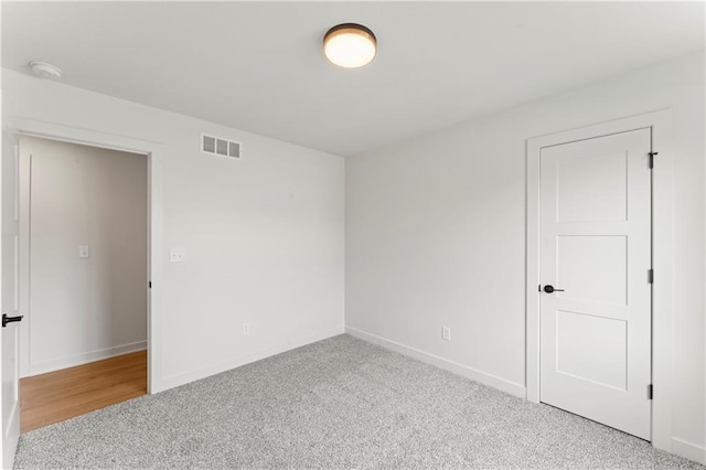 carpeted empty room with visible vents and baseboards