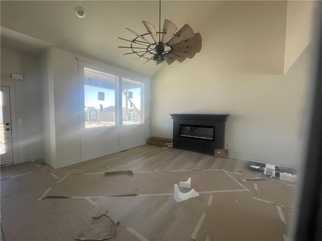 unfurnished living room with lofted ceiling and a glass covered fireplace