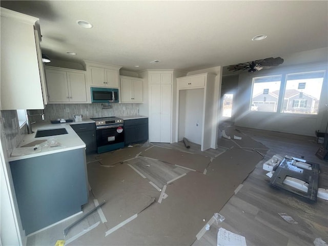 kitchen with light countertops, decorative backsplash, appliances with stainless steel finishes, white cabinetry, and a sink