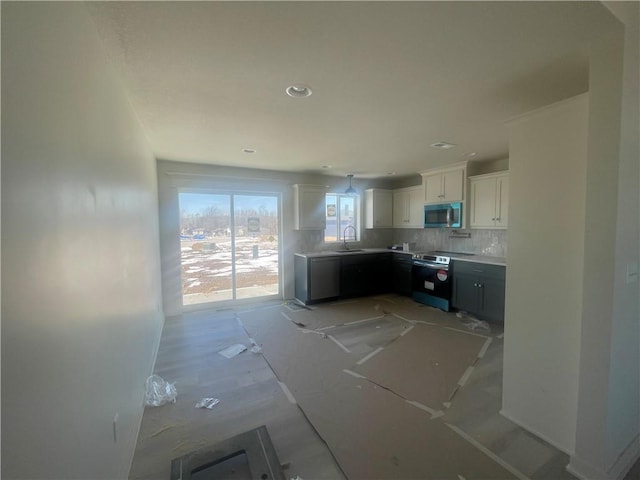 kitchen featuring decorative backsplash, stainless steel appliances, light countertops, white cabinetry, and a sink