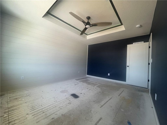 unfurnished room featuring ceiling fan, baseboards, and a raised ceiling