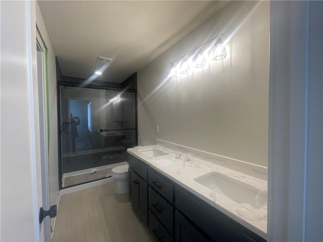 bathroom with double vanity, visible vents, toilet, a sink, and a shower stall