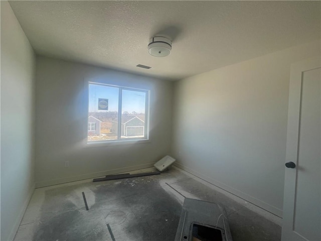 unfurnished room featuring visible vents, a textured ceiling, and baseboards