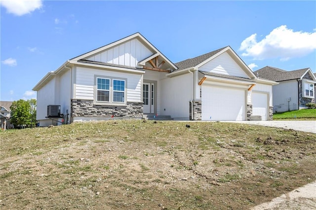 view of front facade with central AC unit, board and batten siding, a garage, stone siding, and driveway