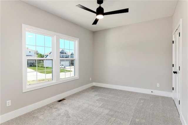 carpeted empty room with visible vents, ceiling fan, and baseboards