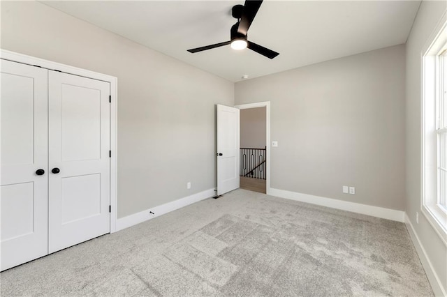 unfurnished bedroom featuring a closet, carpet flooring, a ceiling fan, and baseboards