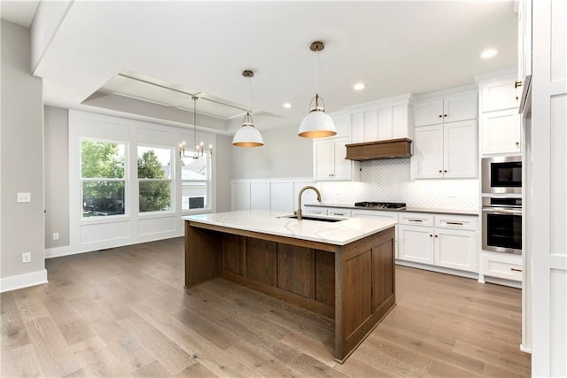 kitchen featuring a sink, white cabinets, appliances with stainless steel finishes, decorative backsplash, and a raised ceiling