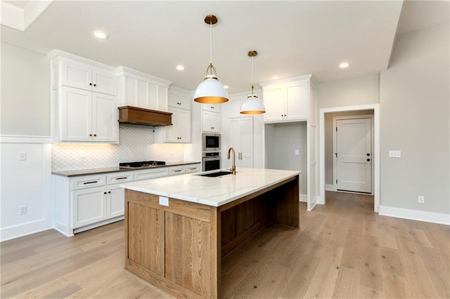 kitchen with light wood finished floors, appliances with stainless steel finishes, a sink, and decorative backsplash