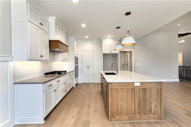 kitchen featuring stainless steel appliances, tasteful backsplash, a sink, and light wood-style flooring