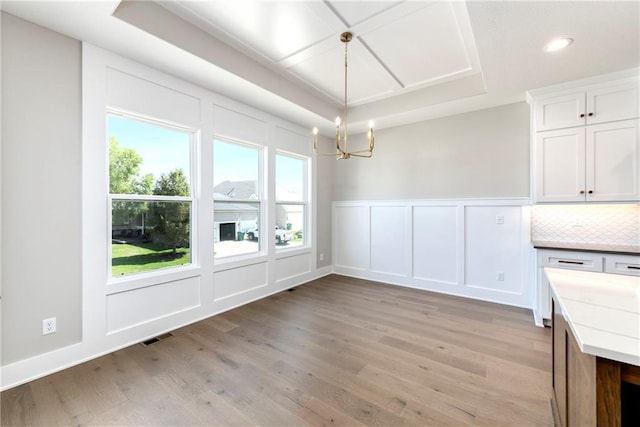 unfurnished dining area featuring visible vents, wainscoting, light wood-style floors, a decorative wall, and recessed lighting