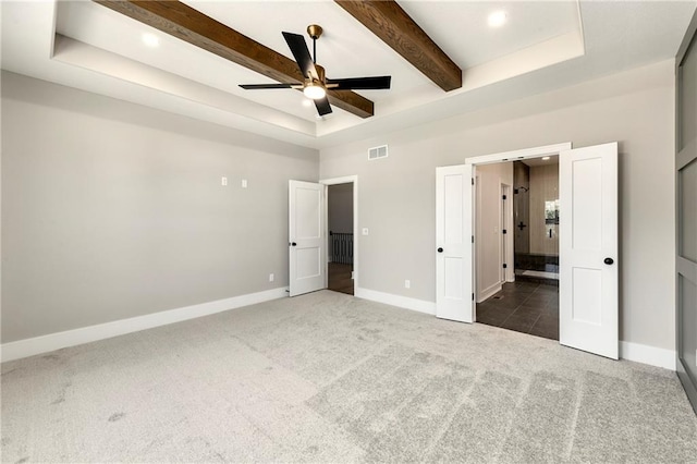 unfurnished bedroom with carpet, beam ceiling, a tray ceiling, visible vents, and baseboards