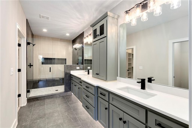 full bath featuring visible vents, a sink, a shower stall, and double vanity