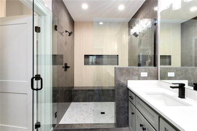 full bathroom with a stall shower, vanity, tile walls, and recessed lighting