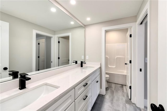 bathroom with recessed lighting, a sink, toilet, and double vanity