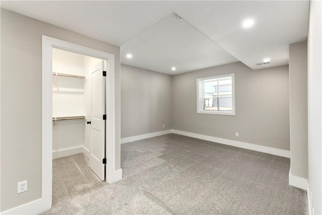 unfurnished bedroom with carpet, a spacious closet, baseboards, and recessed lighting