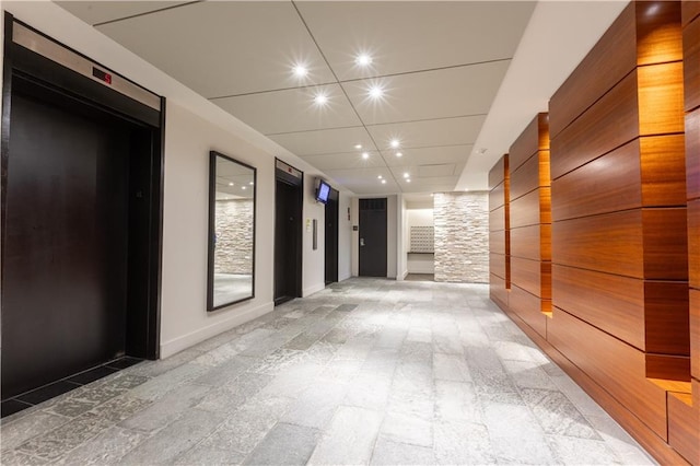 corridor featuring tile flooring, elevator, and a paneled ceiling