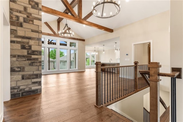 hall featuring a chandelier, high vaulted ceiling, wood-type flooring, and beamed ceiling