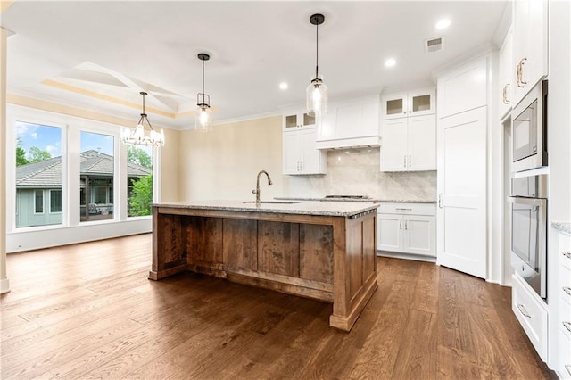 kitchen with wood-type flooring, white cabinetry, appliances with stainless steel finishes, and a kitchen island with sink