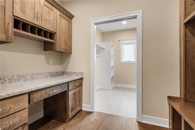 kitchen with built in desk, dark hardwood / wood-style flooring, and light stone counters