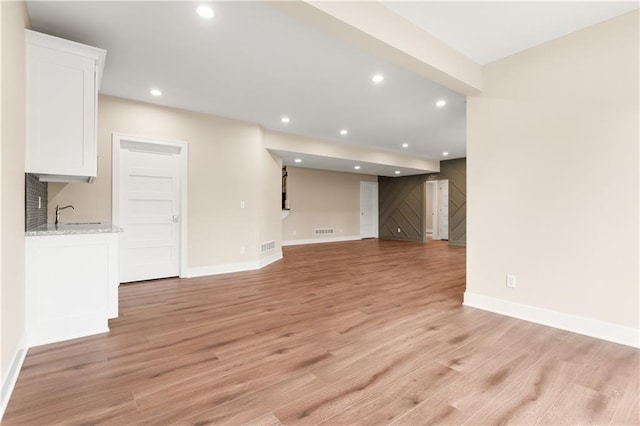 unfurnished living room featuring sink and light hardwood / wood-style floors